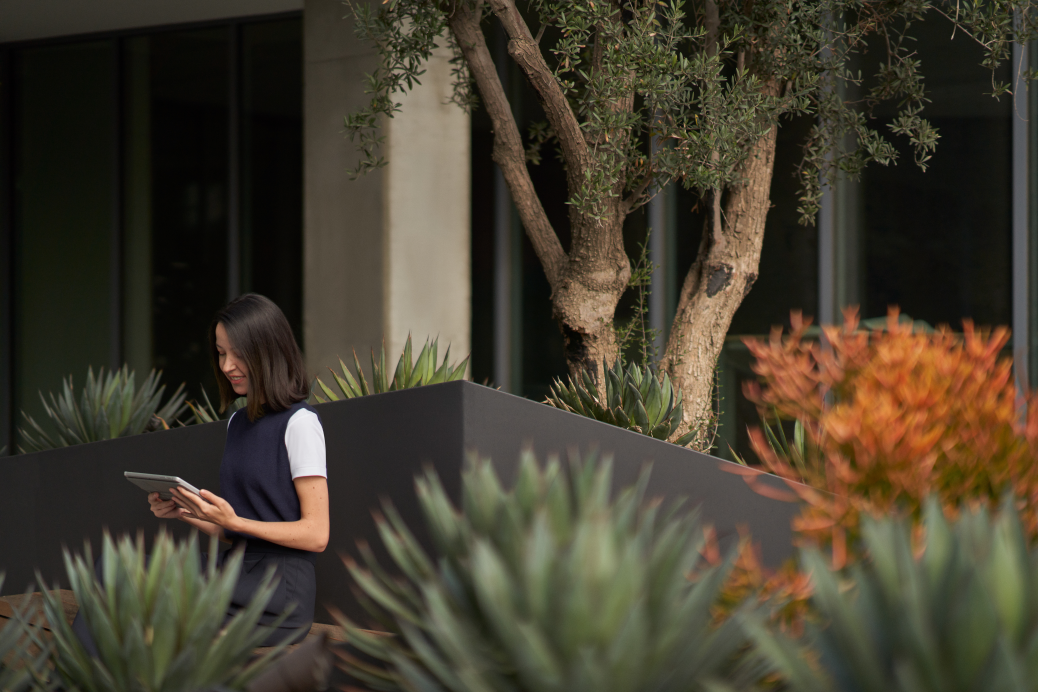 Woman standing in an office garden with a tablet laptop