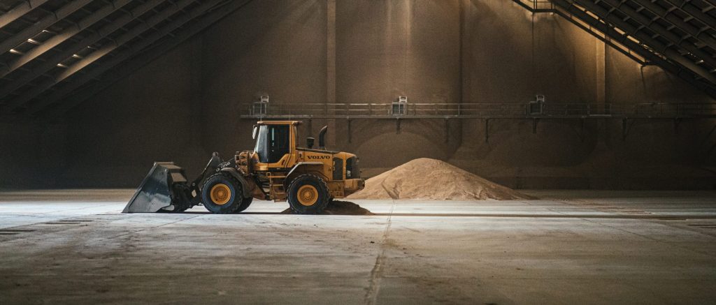 A tractor truck infront of a pile of grains