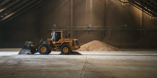 A tractor truck infront of a pile of grains