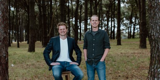 Two adult men standing in the middle of a forest