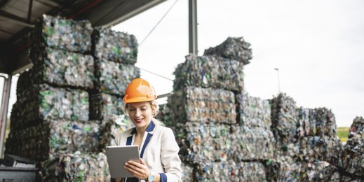 Close-up of female environmental expert using digital tablet for notes while conducting satisfying onsite inspection of recycling facility.