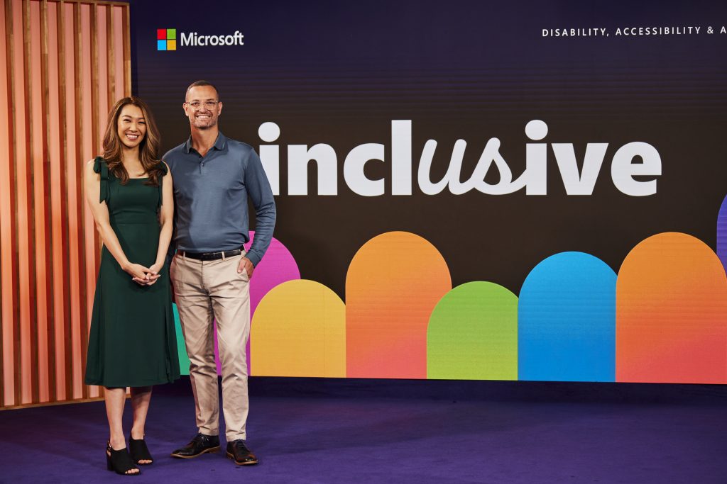 Adult female and male standing side by side infront of the inclusive event sign