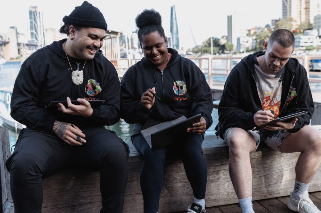 Three adult Indigenous artists collaborating on a Microsoft Surface