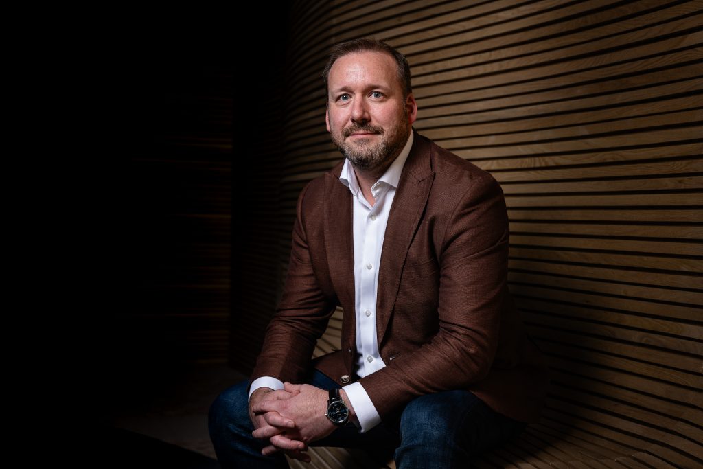 Adult caucasian man, wearing a maroon blazer and white business shirt