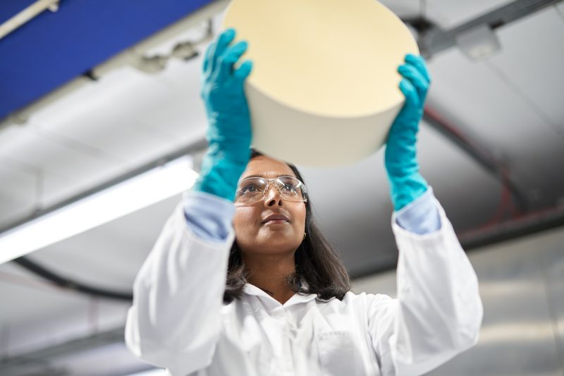 A person wearing gloves holds in front of her a monolith