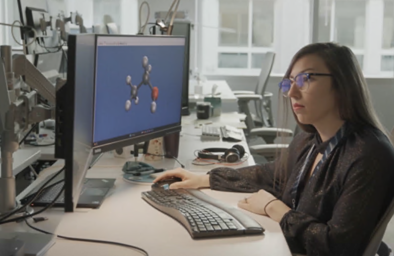 A scientist sits at a desk and works on a computer