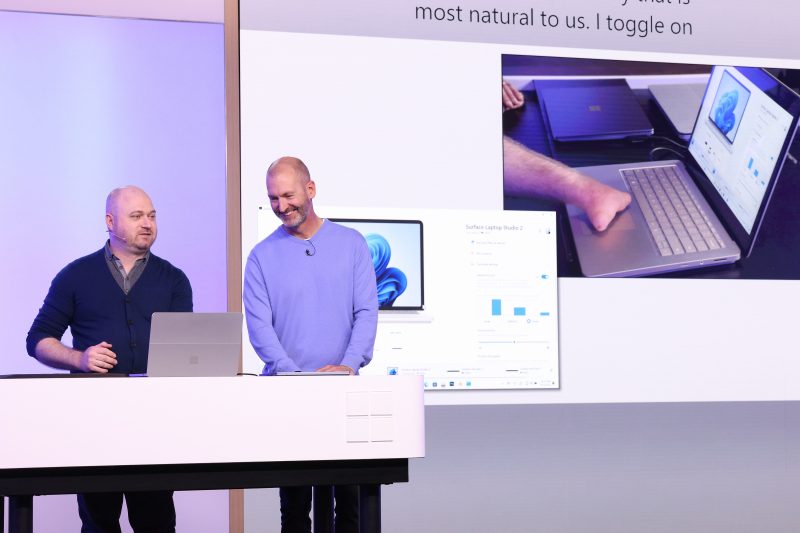 Image of Brett Ostrum, Microsoft corporate vice president for Surface devices, speaking on stage with Solomon Romney, Microsoft accessibility program manager.