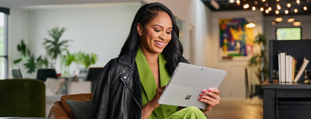 A woman sits in an office holding a Surface tablet.