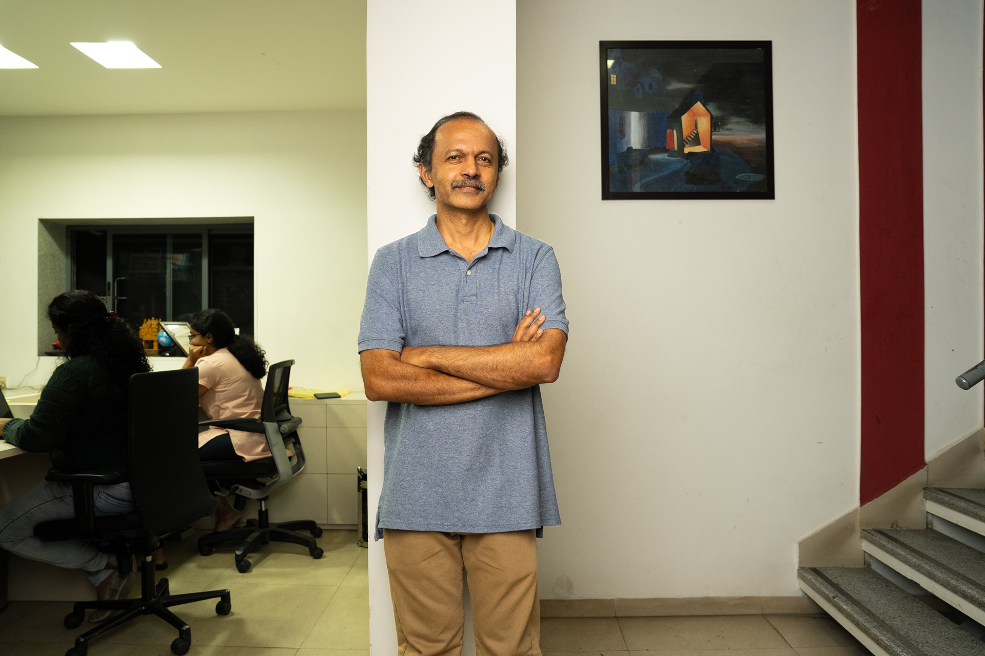 A man standing with arms crossed in an office 