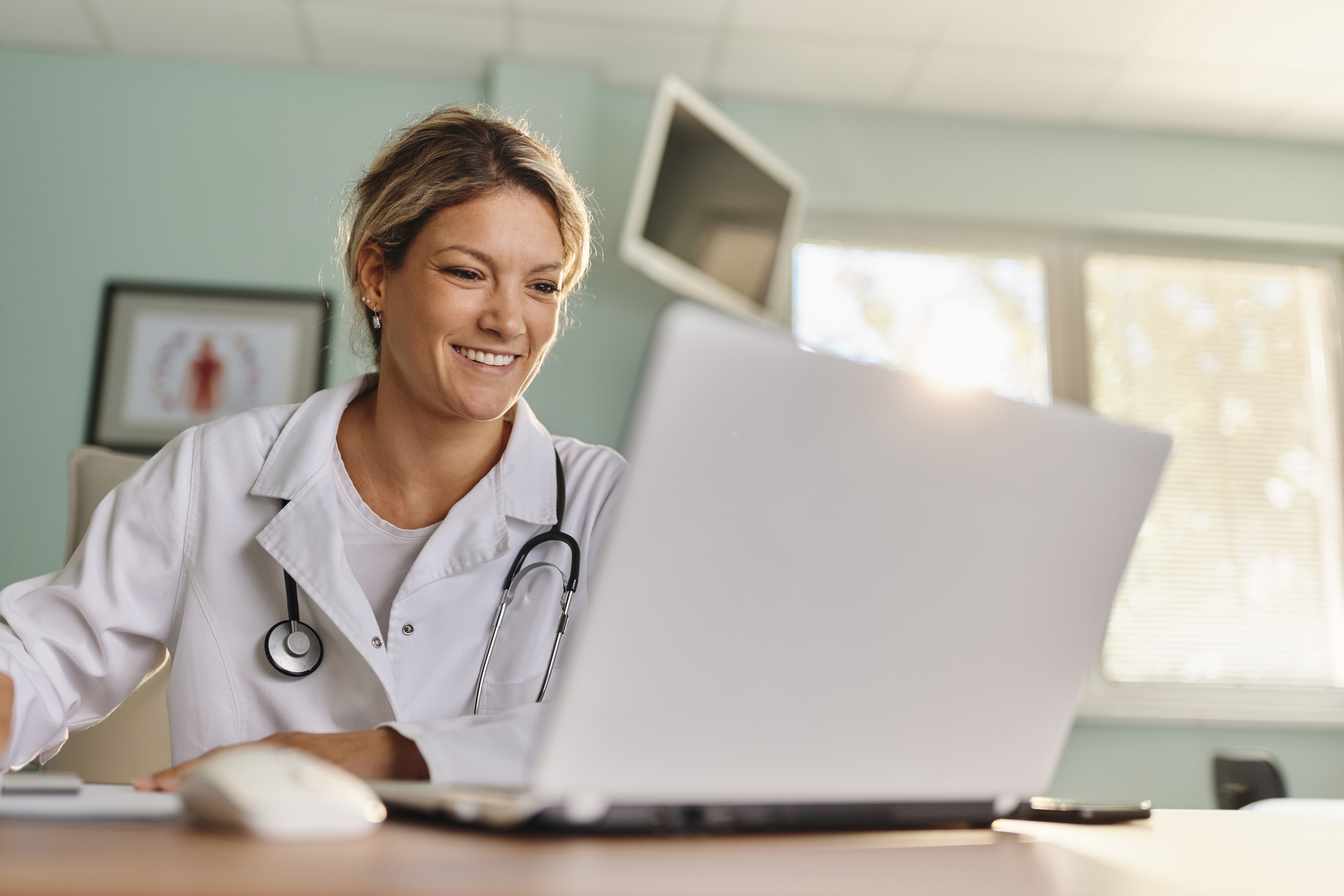 Happy medical expert reading an e-mail on a computer in the office at hospital.