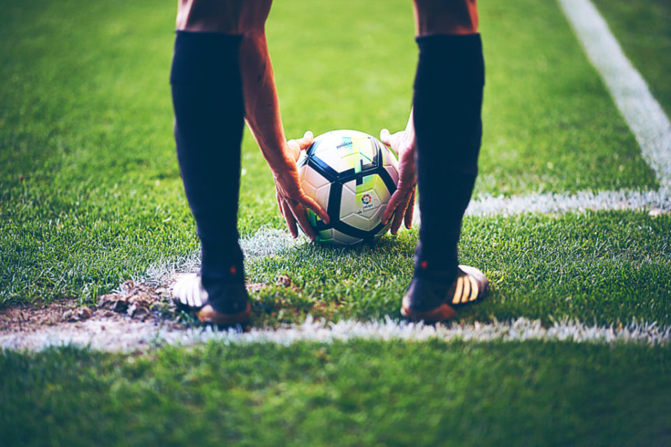 Football player bending down to place ball on field