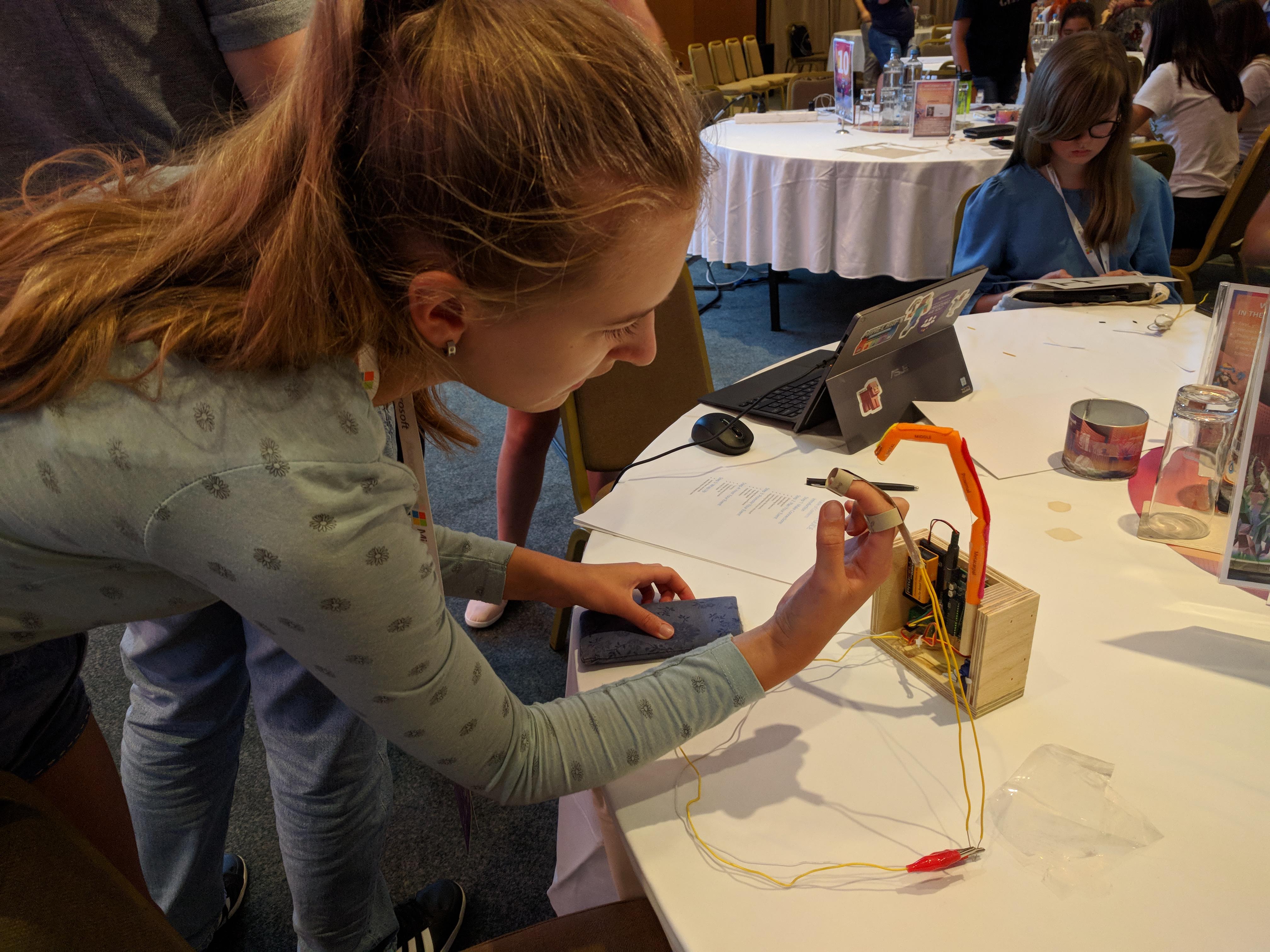 Girl helping another girl create a robotic finger